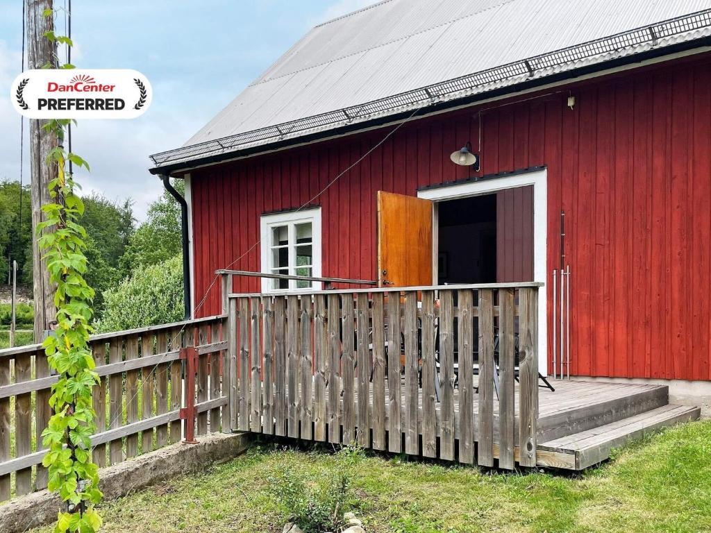 a red house with a wooden fence in front of it at 4 star holiday home in SVÄNGSTA in Svängsta