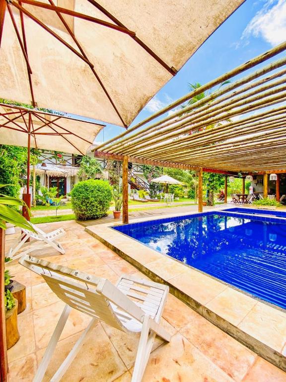 ein Swimmingpool mit zwei Stühlen und einem Sonnenschirm in der Unterkunft Bougainville Icaraí de Amontada in Amontada