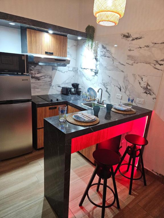 a kitchen with a counter with red bar stools at Villa Molina Del Mar in Arecibo