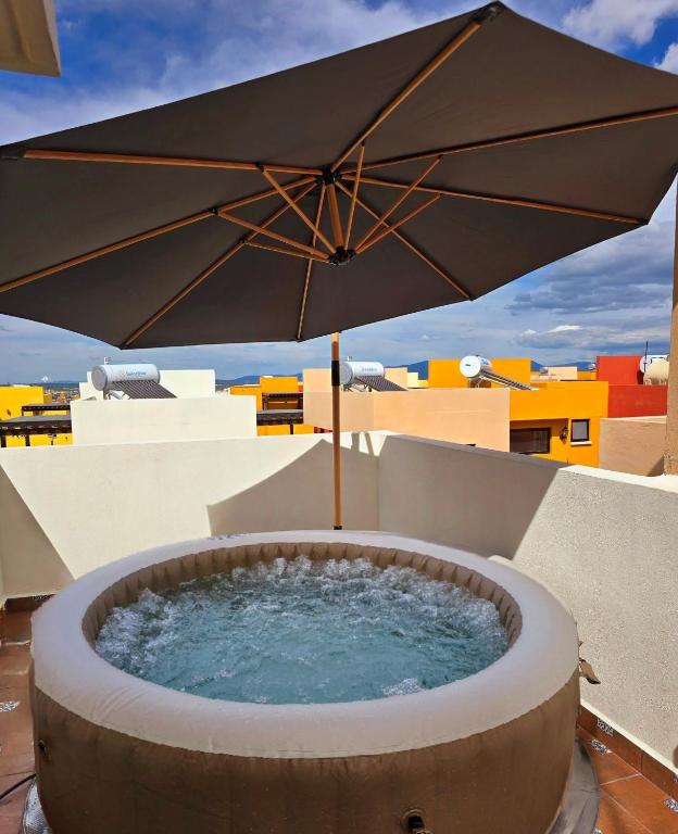 a hot tub with an umbrella on a balcony at Casa Fray in San Miguel de Allende