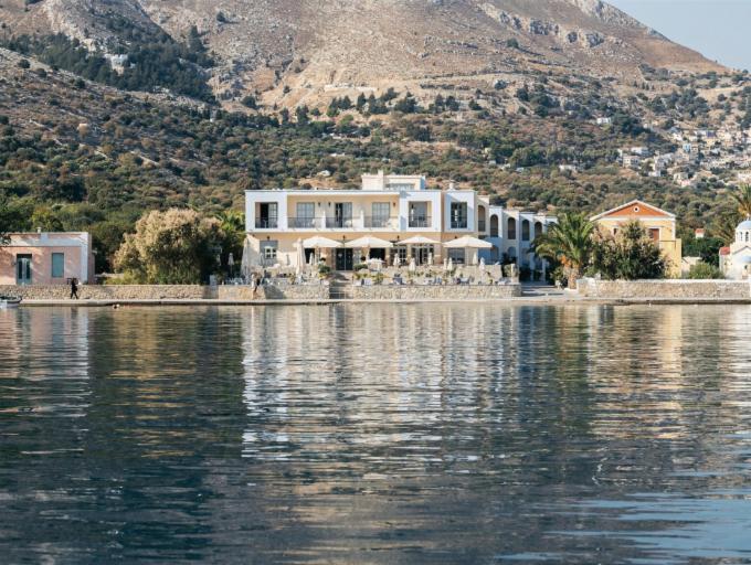 a large house on the shore of a body of water at Pedi Beach Hotel in Symi