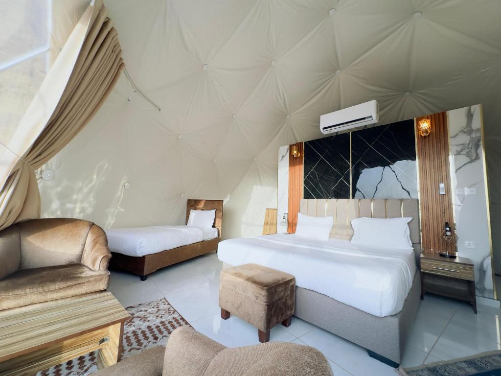 a bedroom with two beds and a chair and a couch at Rum STAR luxury camp in Wadi Rum