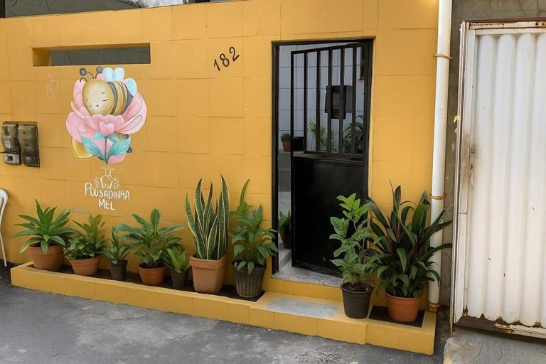 a yellow building with potted plants in front of a door at Casa Pousadinha Mel- QUARTOS E DORMITORIOS in Salvador