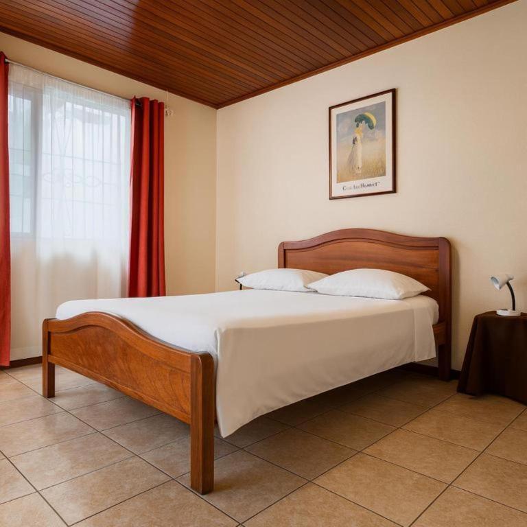 a bedroom with a bed and a red curtain at Casa Cafetal Aeropuerto in Alajuela