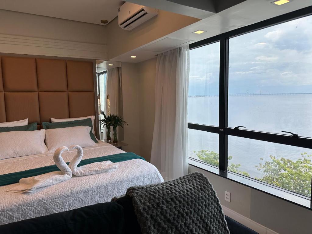Un dormitorio con una cama con una ventana grande. en Tropical Executive Flat Suites 507 view, en Manaus