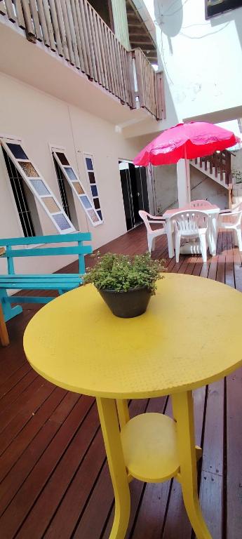 a yellow table with a potted plant on a deck at Margarida pousada in Garopaba