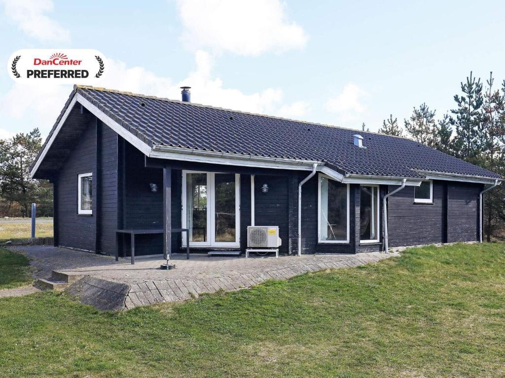 a black house with a bench in front of it at 9 person holiday home in Hurup Thy-By Traum in Sindrup