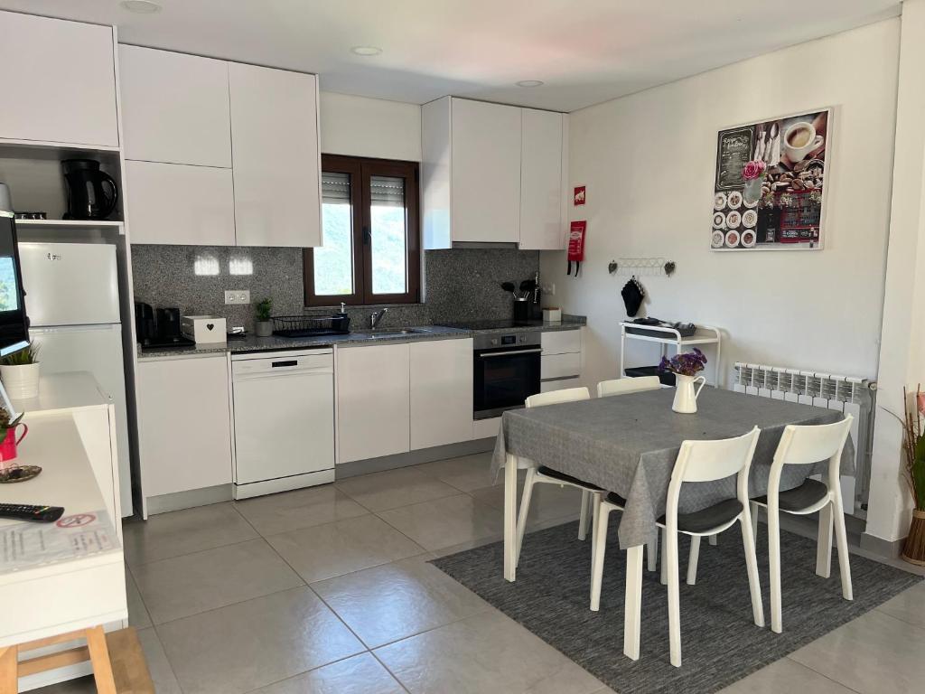 a kitchen with white cabinets and a table and chairs at Casa da Laija - Vistas rio, campo e montanha in Cova
