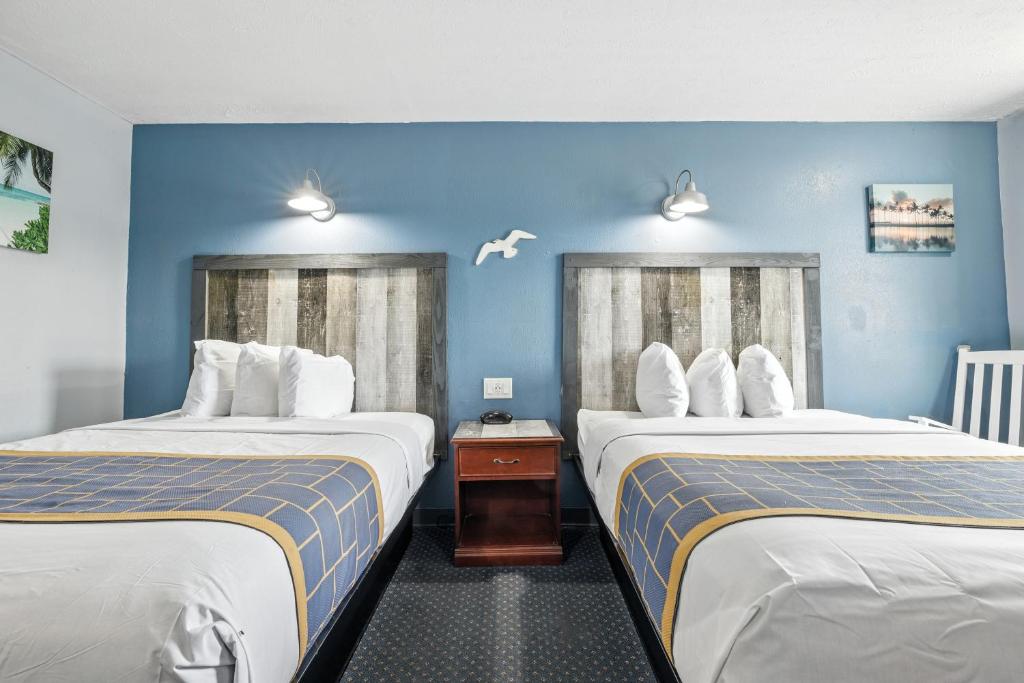 two beds in a hotel room with blue walls at Days Inn & Suites by Wyndham Terre Haute in Terre Haute