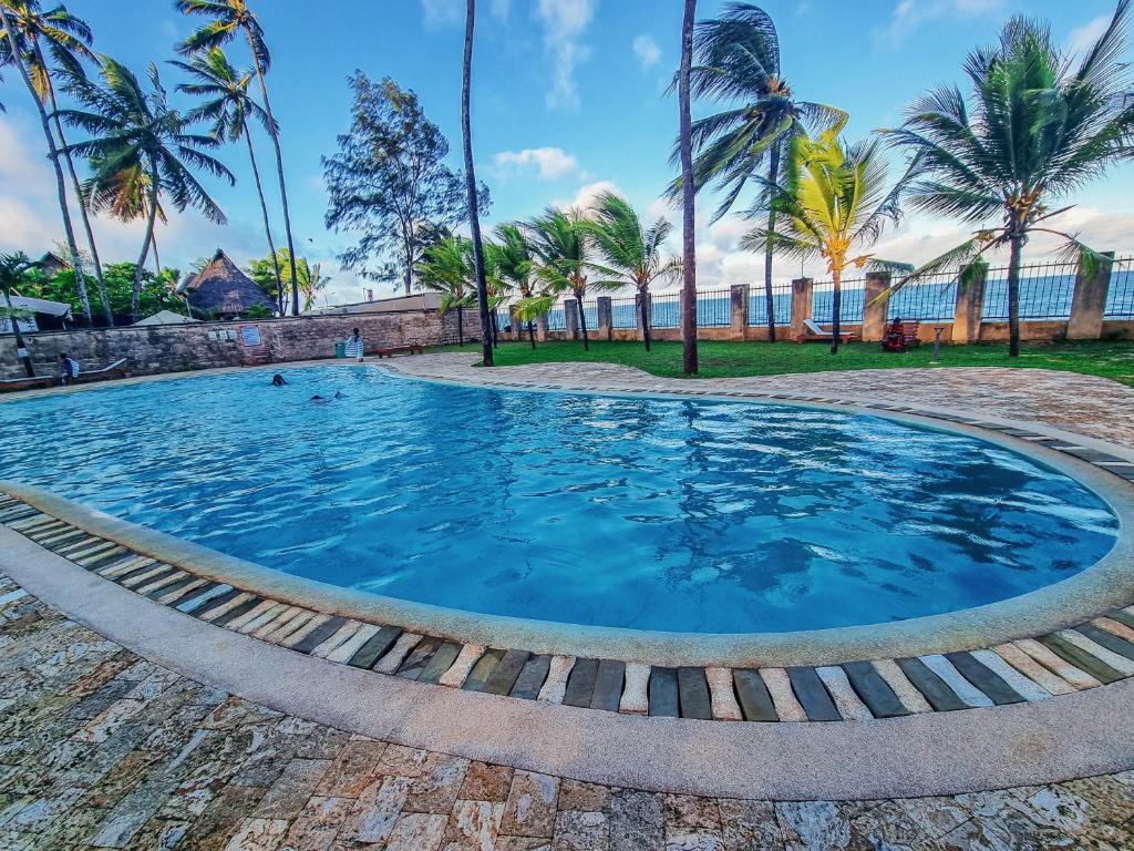 モンバサにあるPenthouse with Stunning Beachfront Viewsのヤシの木が背景に広いスイミングプール