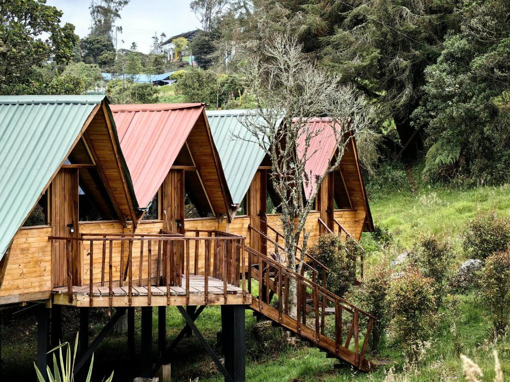 Una cabaña de madera con terraza y techo rojo. en Cabañas del bosque, en Choachí