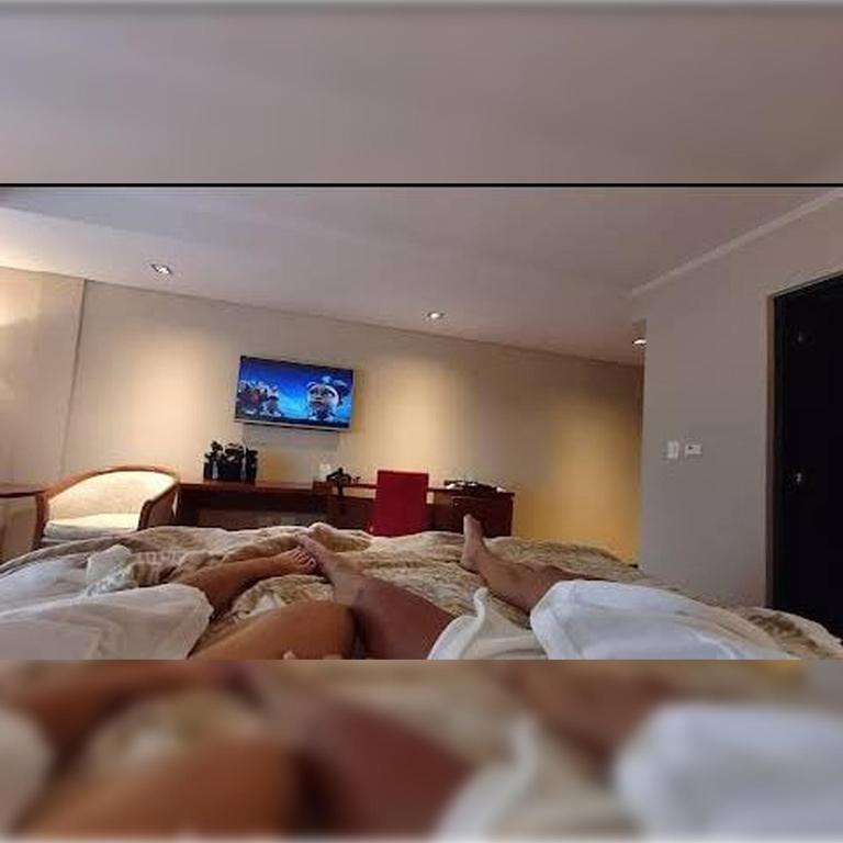 Una mujer acostada encima de una cama con un televisor. en Iguazu Hotel, en Puerto Iguazú