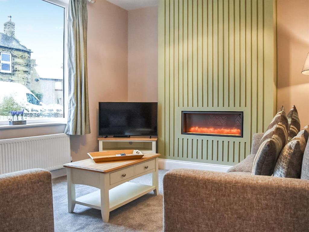 ein Wohnzimmer mit Kamin und Fernseher in der Unterkunft Lavender Cottage in Seahouses