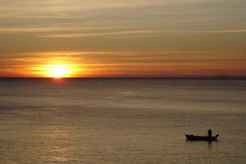 a man in a boat in the ocean at sunset at Apartment in Pula - Istrien 11070 in Veruda