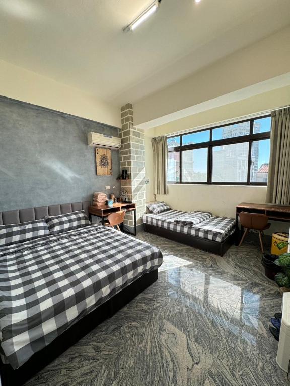 a bedroom with two beds and a desk and windows at 大橋旁民宿 in Jincheng