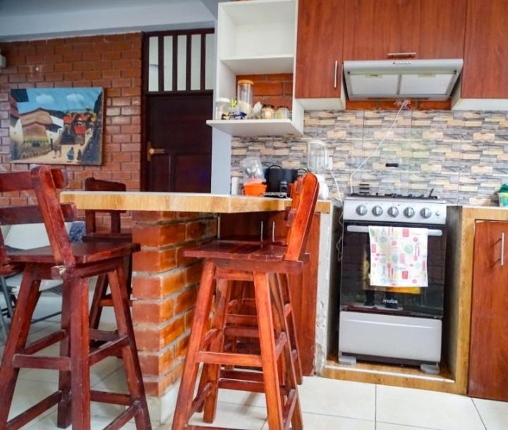 cocina con encimera con taburetes y horno en Casita Tingo María, en Tingo María