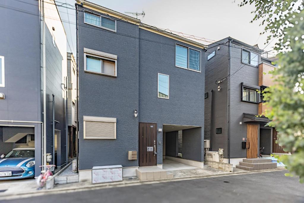 un edificio azul con un coche aparcado delante de él en 7 min walk from JR Yamanote Line Uguisudani Spacious 4-Bedroom House near Ueno & Asakusa With Parking, en Tokio