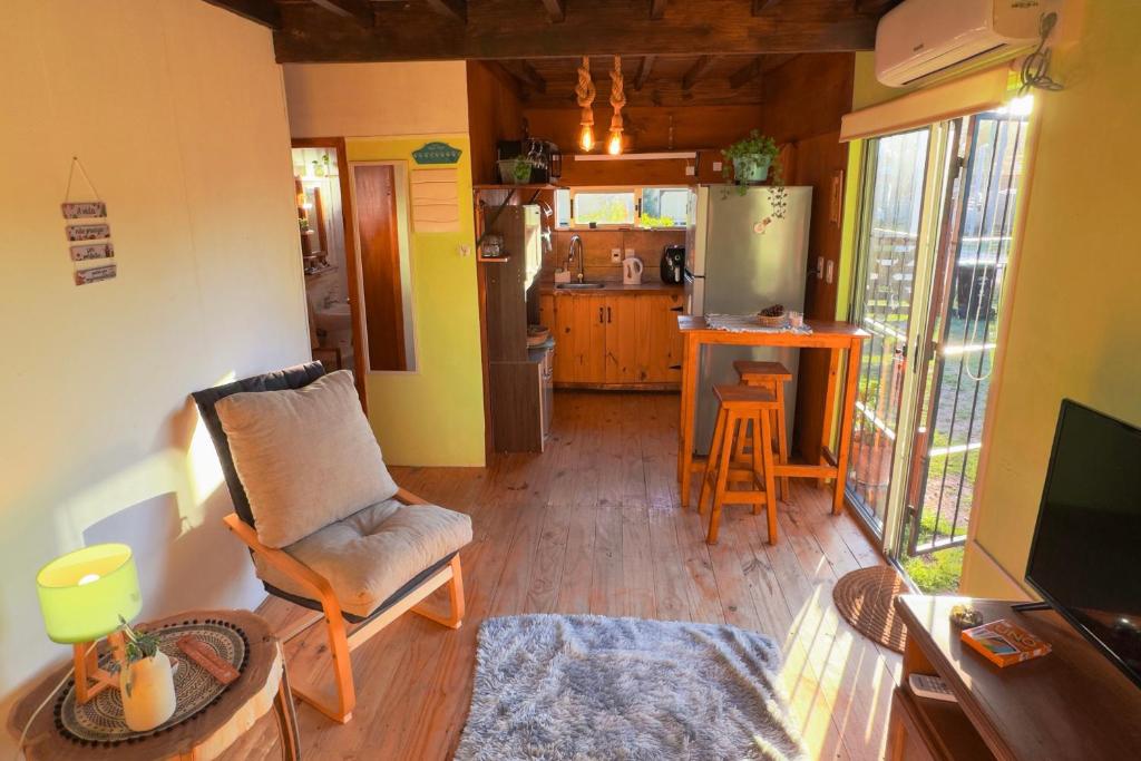 a living room with a chair and a kitchen at Beautiful romantic cabin for a relaxing getaway in Ciudad de la Costa