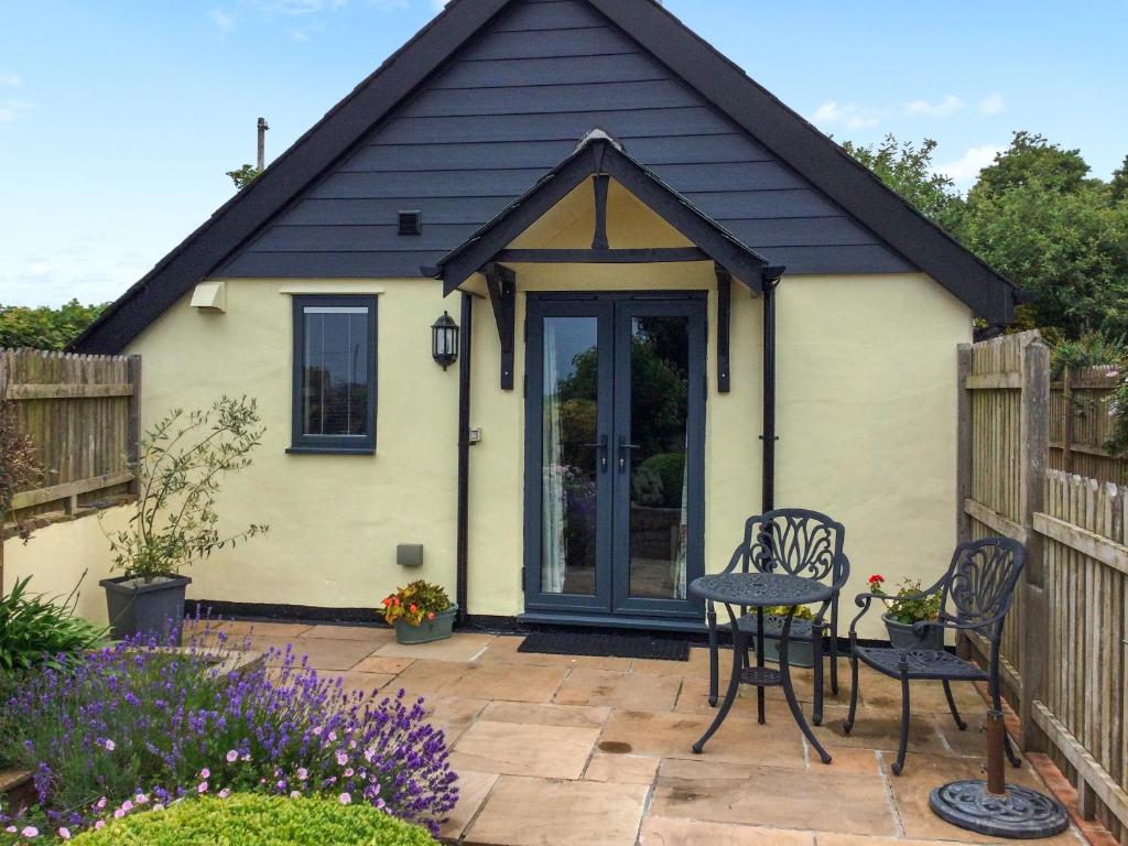 a cottage with a table and chairs on a patio at The Bothy in Bradworthy