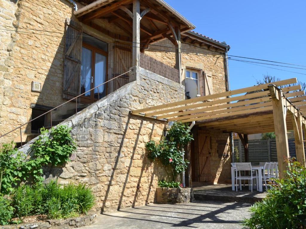 a stone house with a wooden pergola at Maison de charme, terrasse ombragée près de Sarlat - FR-1-616-475 in Groléjac
