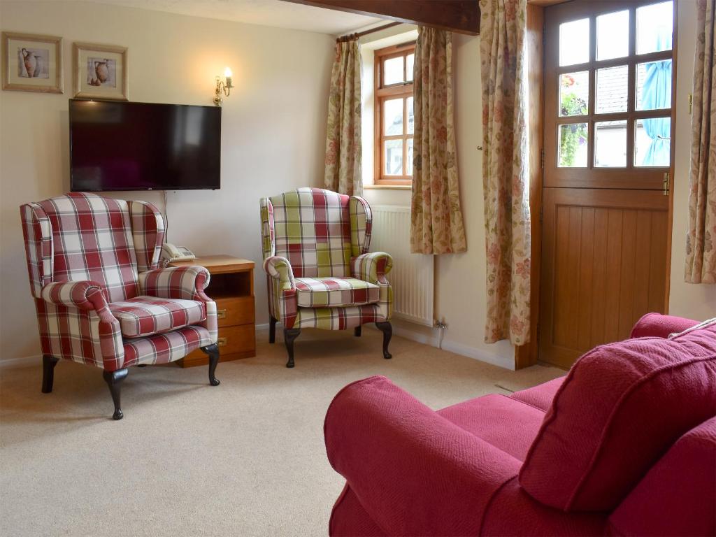 a living room with two chairs and a tv at The Milking Parlour in Sidbury