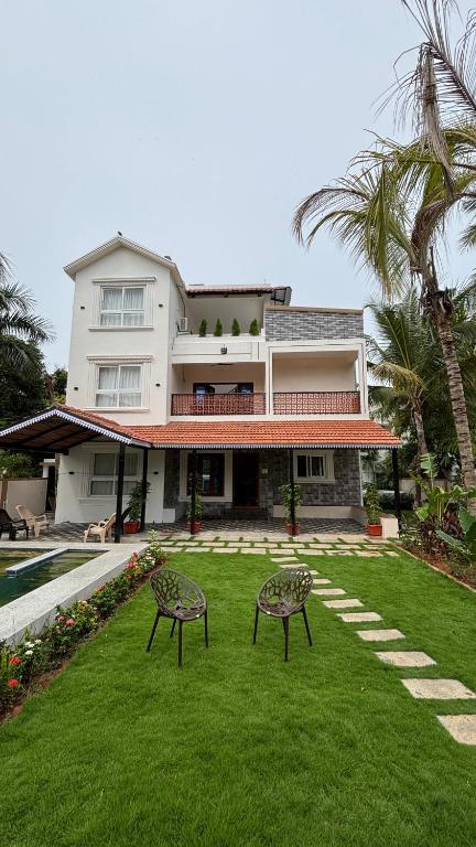 a house with two chairs in the yard at Villa19, ECR in Tirupporūr