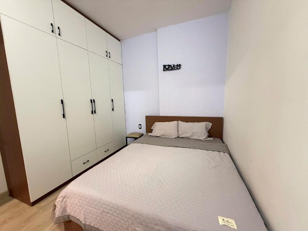 a small bedroom with a bed and white cabinets at Sun House in Kinh Dinh