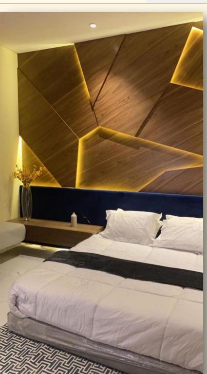 une chambre avec un grand lit avec une tête de lit en bois dans l'établissement فندق نخبة العارض, à Riyad