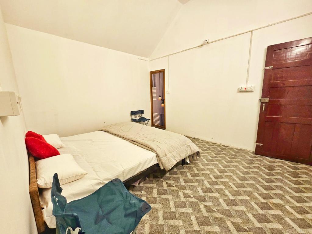 a bedroom with a bed and a wooden door at Tribano vattavada in Vattavada