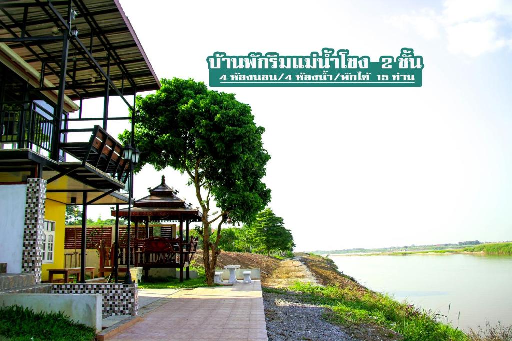 a walkway next to a river with a building at Mekong Tarawadee Villa in Tha Bo