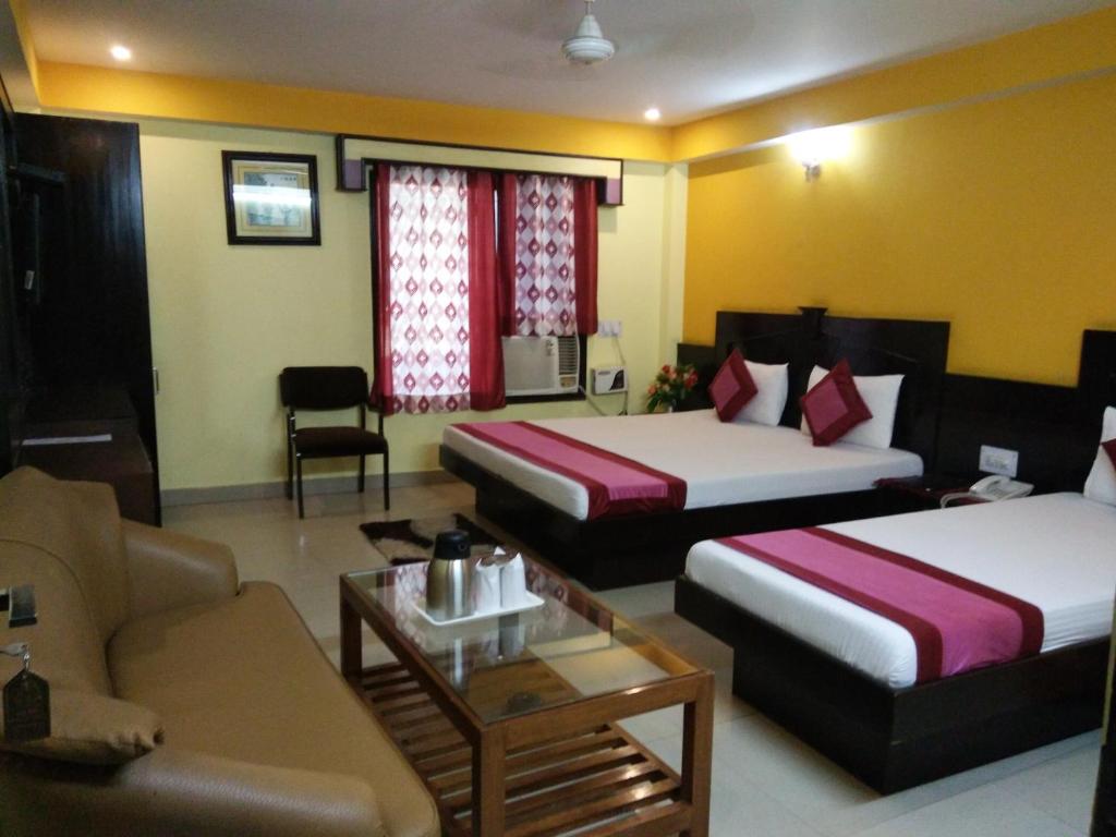 een hotelkamer met 2 bedden en een bank bij Hotel Su Shree Continental 5 Minutes Walk From New Delhi Railway Station in New Delhi