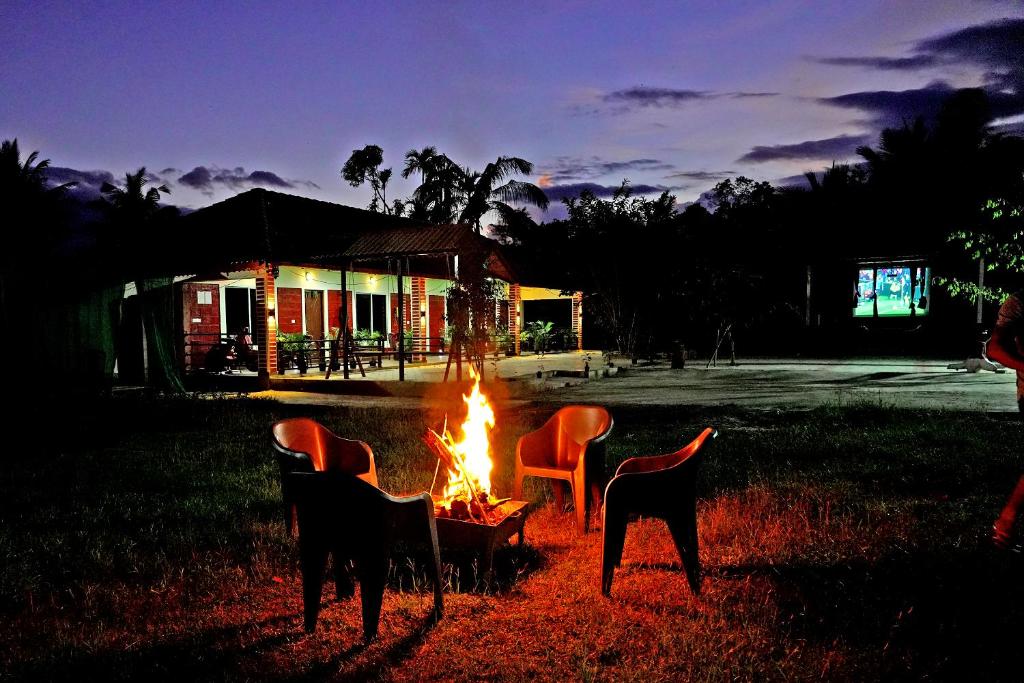 a fire pit with chairs and a dog standing around it at Rainy Cloud Homestay - 1km Falls, Coffee Estate, Campfire, Home Food in Chikmagalūr