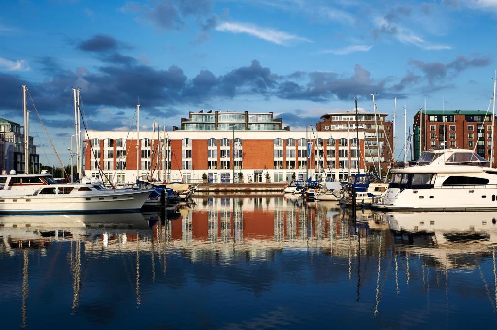 un groupe de bateaux amarrés dans un port avec un bâtiment dans l'établissement Im-Jaich Boardinghouse Bremerhaven, à Bremerhaven