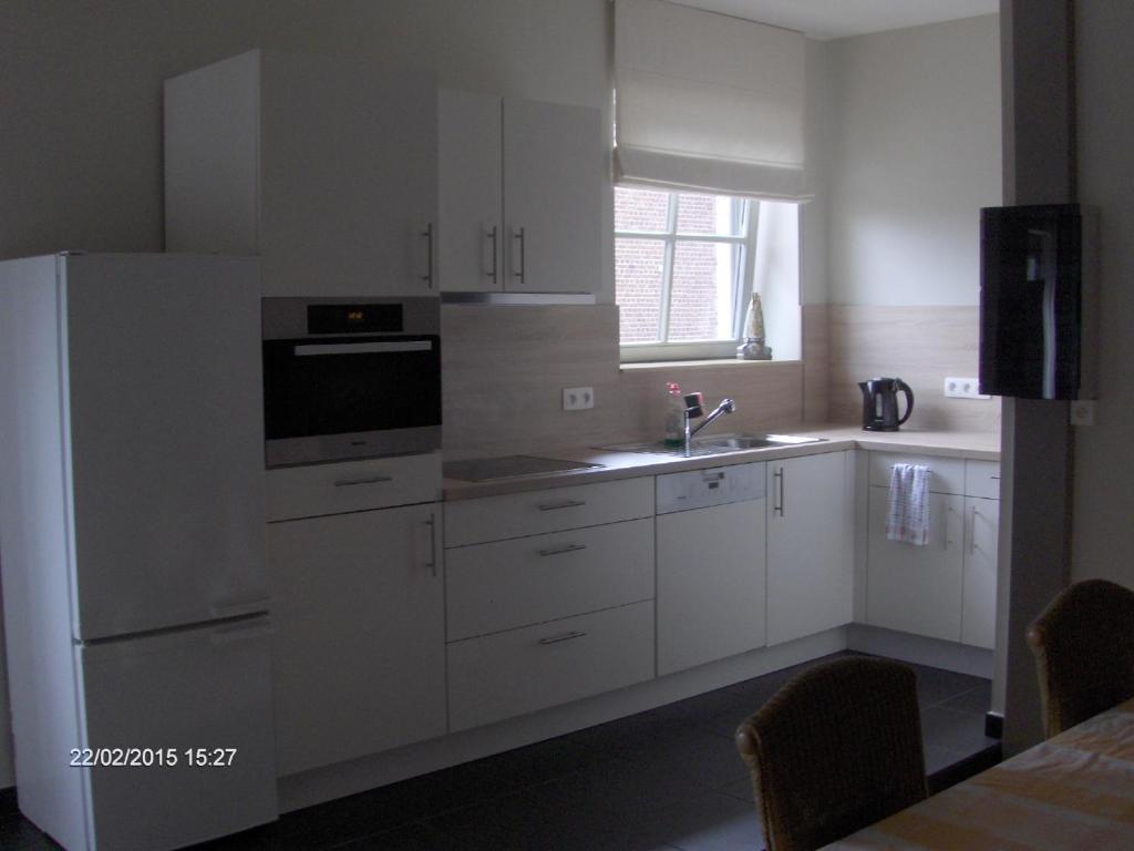 een keuken met witte kasten, een wastafel en een koelkast bij Wenceslas Cobergher Appartement II in Boutersem