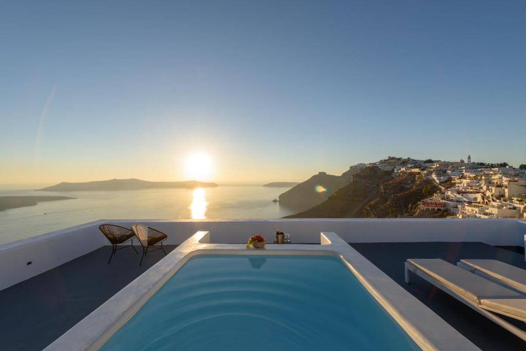 a pool on the roof of a house with the sunset at Aria Suites & Villas in Fira