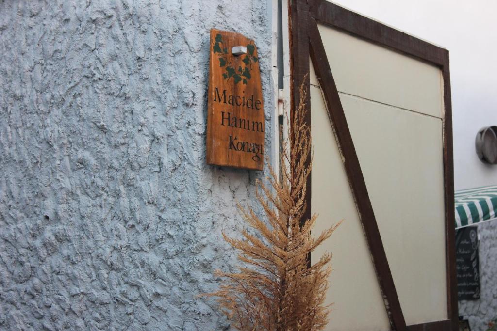una señal en el lateral de un edificio con una planta en Macide Hanım Konağı, en Ayvalık