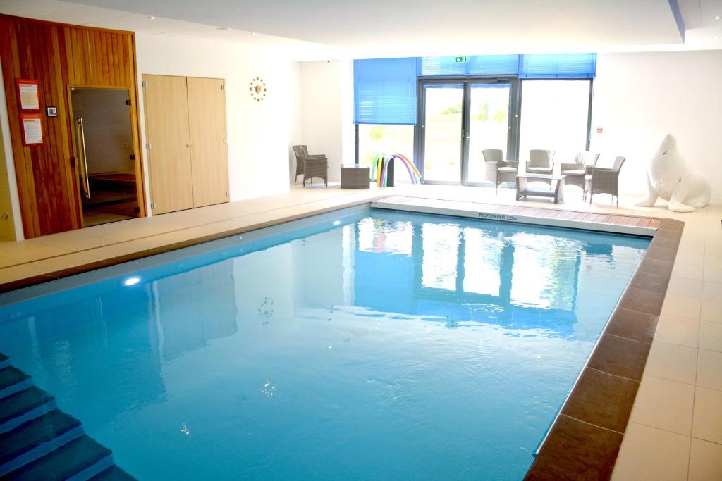 una grande piscina con acqua blu in una stanza di Domitys Le Griffon d’Or a Saint-Brieuc