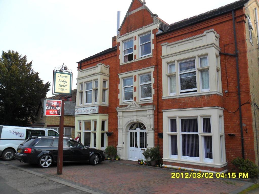 um carro preto estacionado em frente a um edifício de tijolos em Thorpe Lodge Hotel em Peterborough