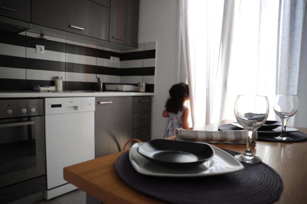 ナクソス・コラにあるSt George beach Apartmentのワイングラス付きテーブルのあるキッチンの女の子