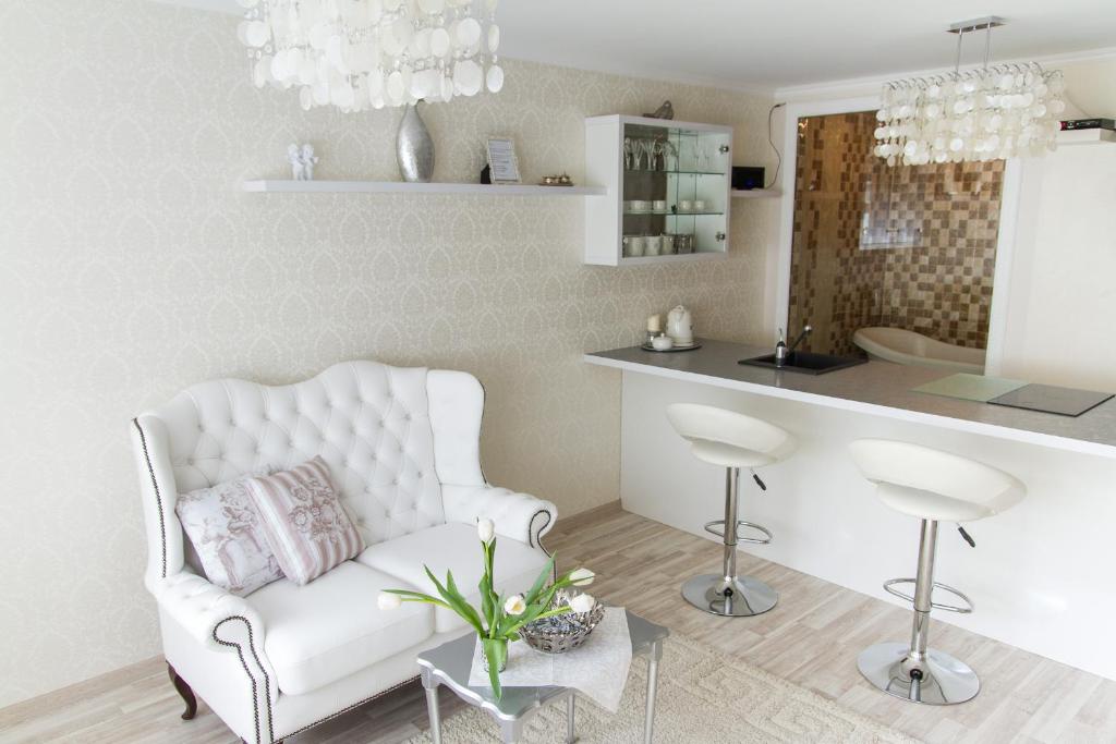 Juozapaviciaus apartments في فيلنيوس: غرفة معيشة مع أريكة بيضاء ومطبخ