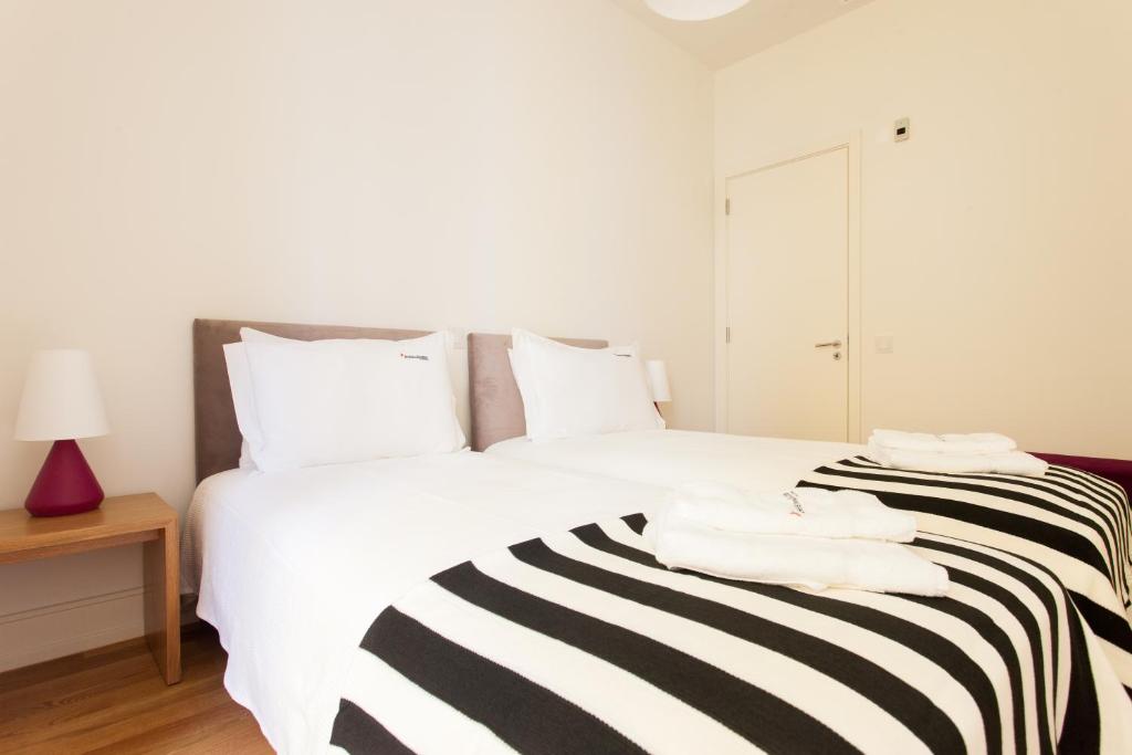 uma cama branca com um cobertor listrado preto e branco em FLH Avenida da Liberdade Modern Flat em Lisboa