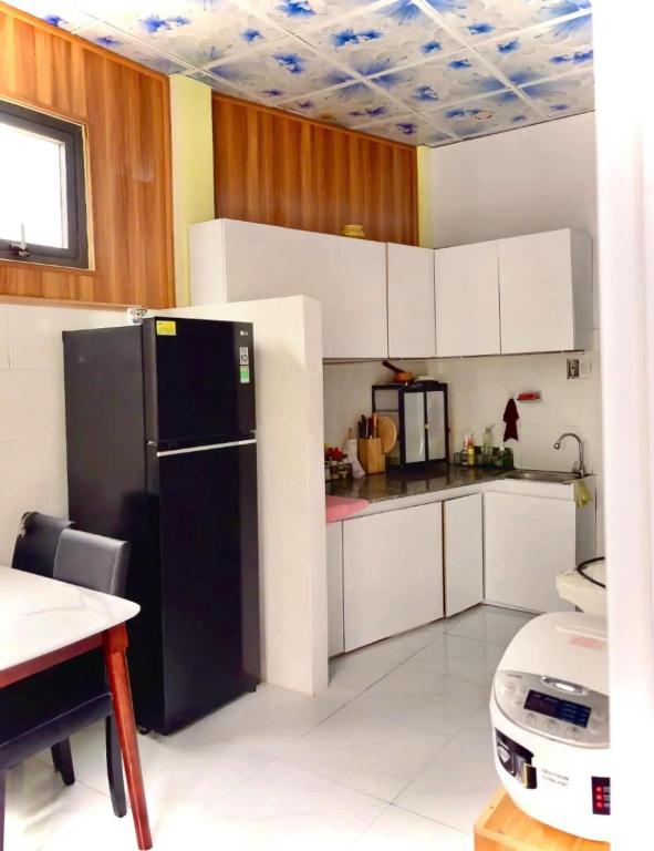 a kitchen with a black refrigerator and white cabinets at Nhà MIO in Khu Chi Lăng