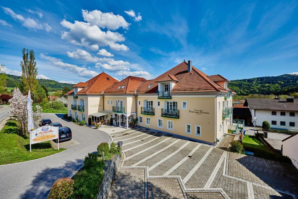 a large house with a parking lot in front of it at AKZENT Hotel Bayerwald-Residenz in Neukirchen