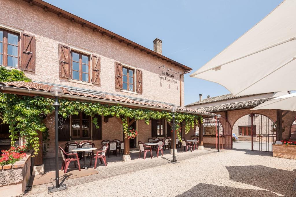 eine Außenterrasse mit Tischen und Stühlen vor einem Gebäude in der Unterkunft Le Relais Des Dix Crus - Logis Hôtel B&B in Corcelles-en-Beaujolais