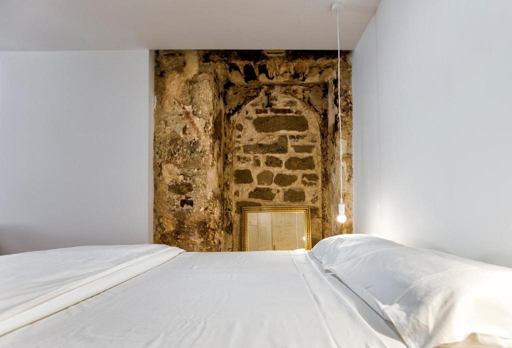 a white bed in a room with a stone wall at Sant' Erasmo's Flat in Alghero