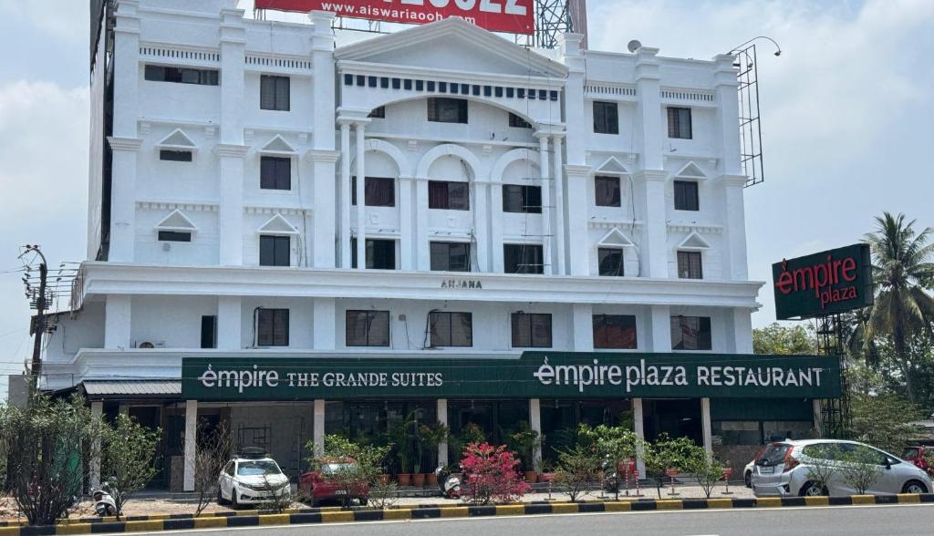 ein weißes Gebäude mit davor geparkten Autos in der Unterkunft EMPIRE THE GRANDE SUITEs in Ernakulam