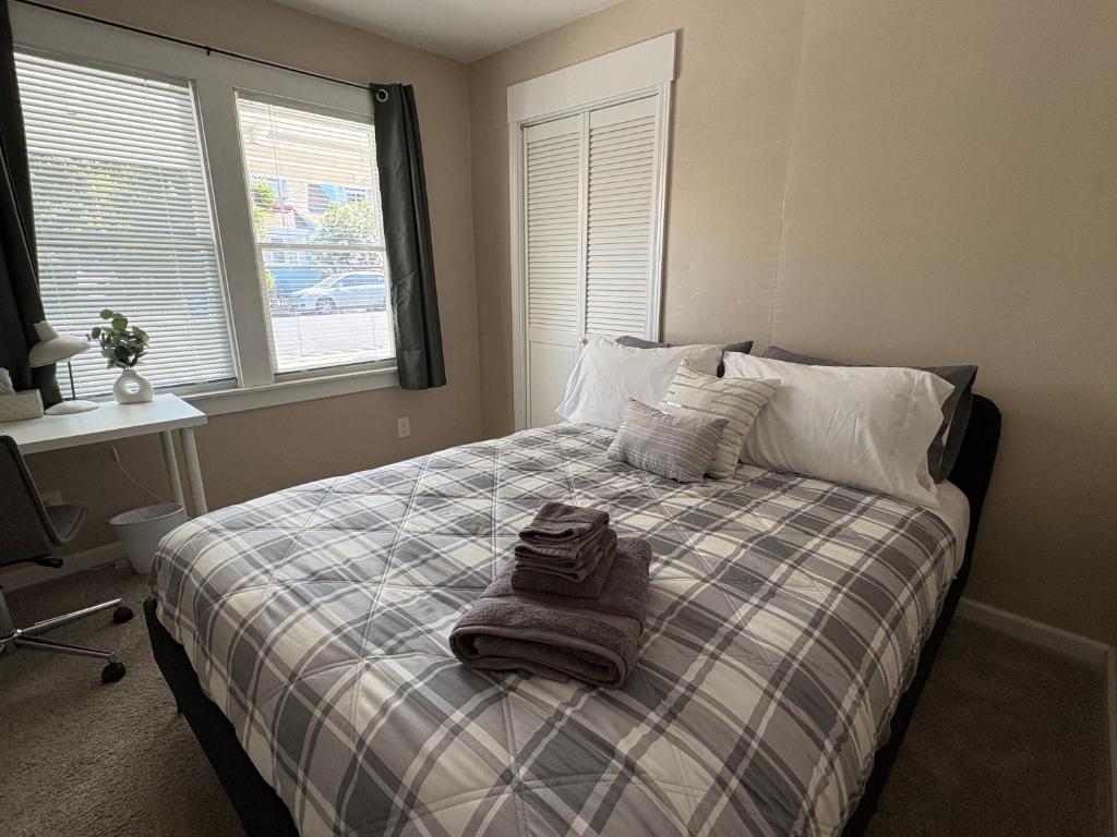 a bedroom with a bed with a blanket and two windows at Comfortable Place, Great Location, Fiber Wifi, and Free Parking in Hayward