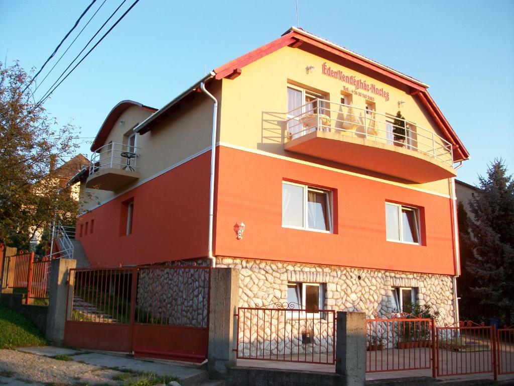 an orange and yellow building with a fence at Éden Vendégház in Miskolctapolca