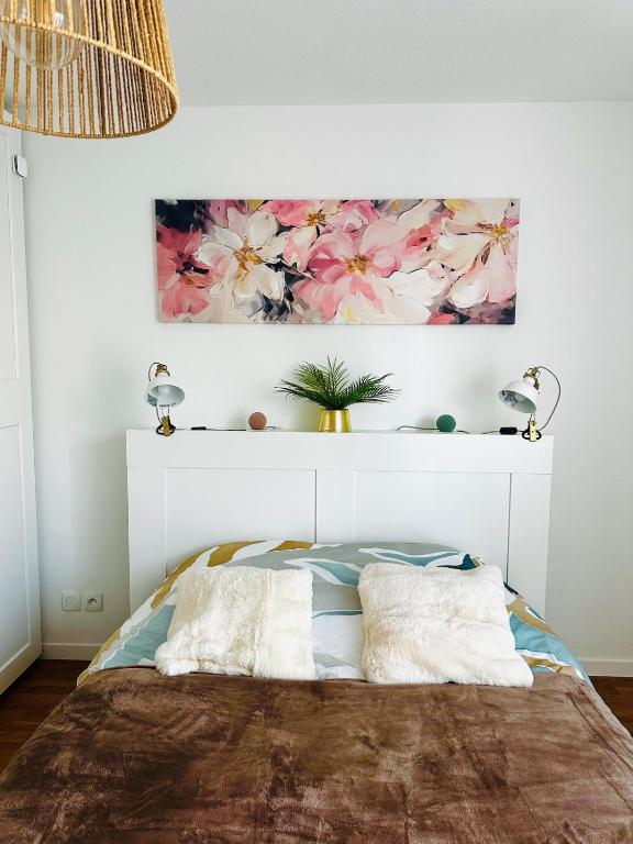 a bedroom with a bed with a painting on the wall at Cocon urbain, appartement 4 personnes avec jardin à 2mn de Vannes, Golfe du Morbihan in Plescop