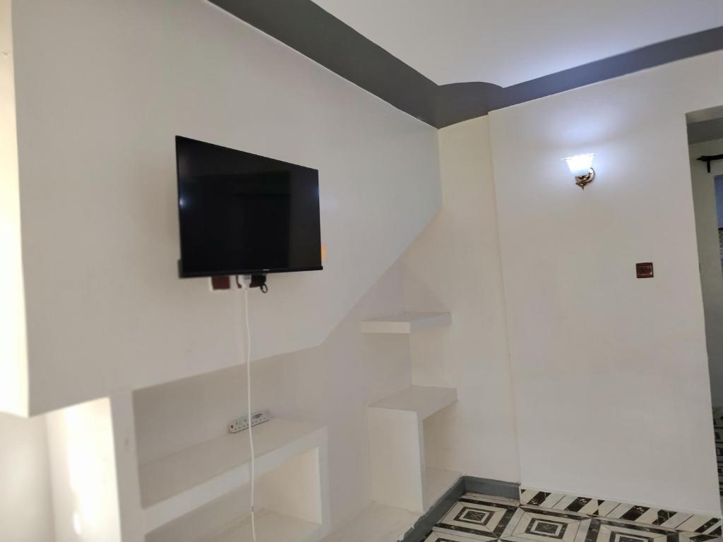 Elle comprend une télévision à écran plat suspendue sur un mur blanc. dans l'établissement Hephy Suites and BnB, à Nairobi